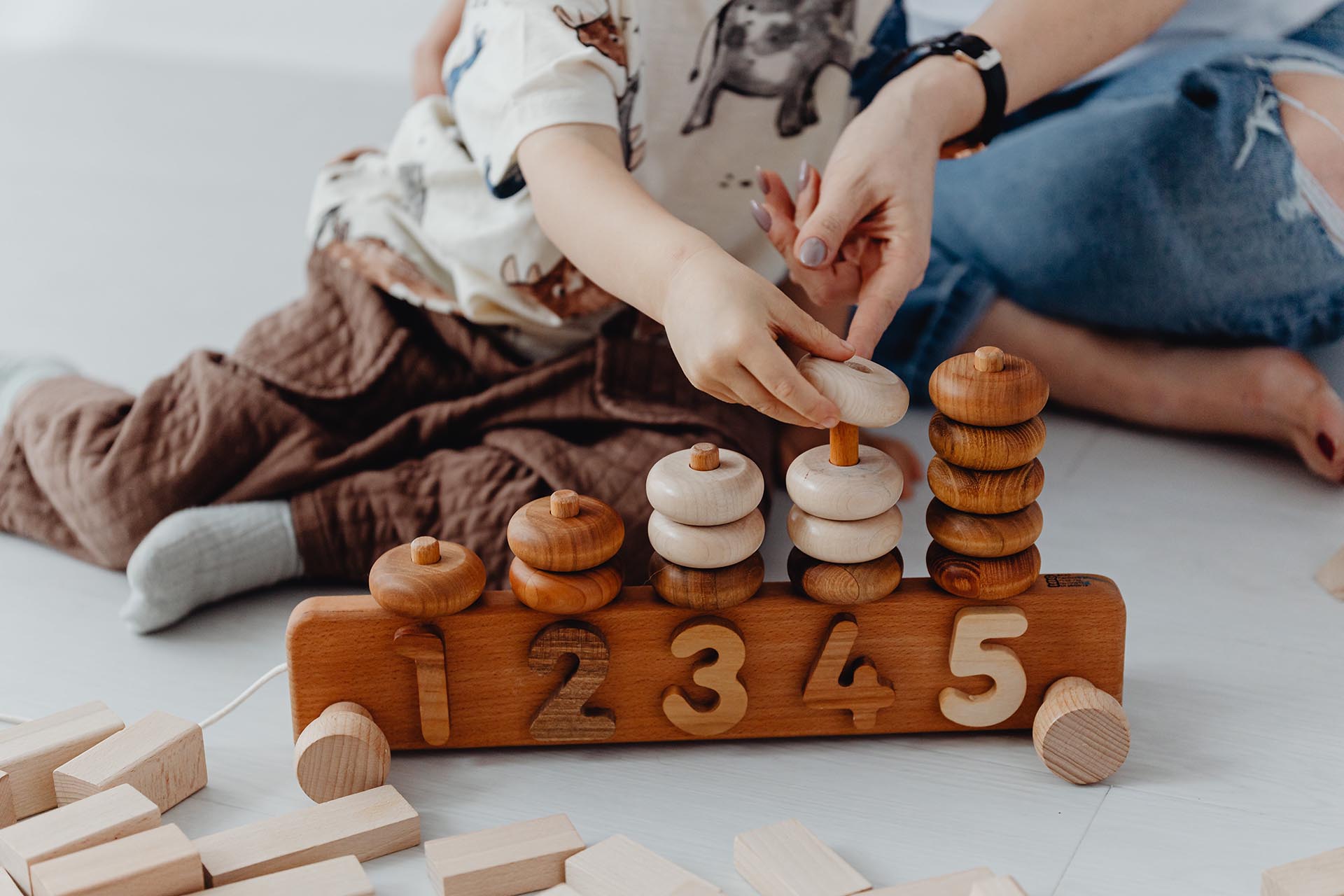 Toddler Putting Wooden Circle Blocks On Educational Numbers Block